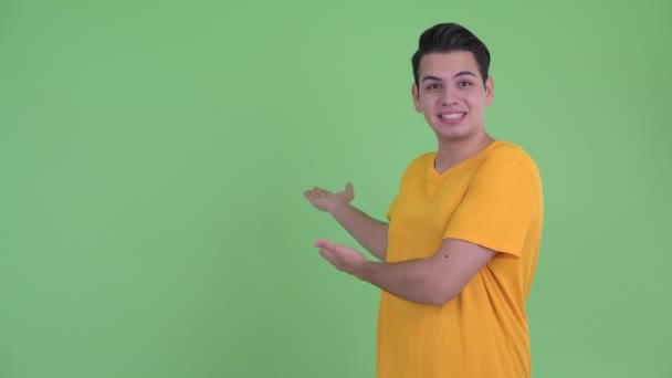 Šťastný mladý multietnický muž, který prezentuje něco zezadu — Stock video