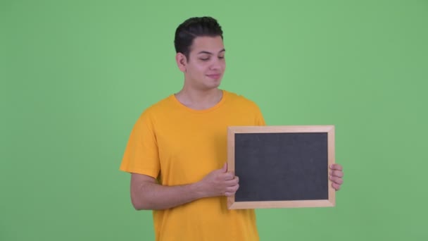 Glücklicher junger multiethnischer Mann hält Tafel und gibt Daumen hoch — Stockvideo