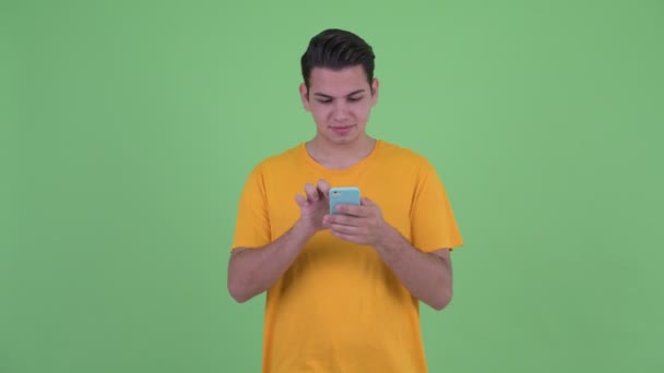 Feliz joven multi étnico hombre usando el teléfono y recibiendo buenas noticias — Vídeo de stock