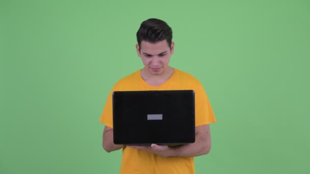 Glücklicher junger multiethnischer Mann, der mit Laptop denkt — Stockvideo