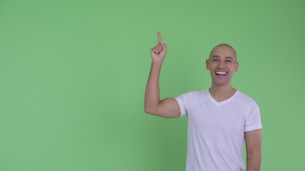 Glücklich schöner glatzköpfiger Mann zeigt nach oben und sieht überrascht aus — Stockvideo