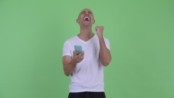 Šťastný hezký holohlavý muž, který používá telefon a dostává dobré zprávy — Stock video