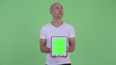Dijital tablet gösterirken mutlu yakışıklı kel adam düşünme