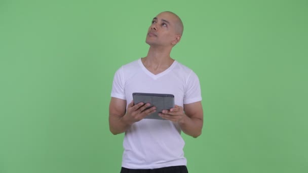 Счастливый красивый лысый мужчина, мыслящий с помощью цифрового планшета — стоковое видео
