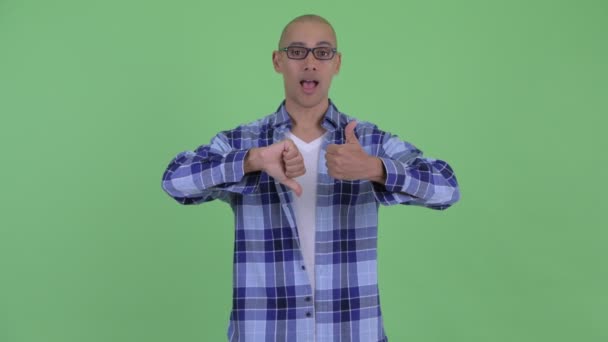親指と親指の間で選択する混乱したハゲヒップスターの男 — ストック動画