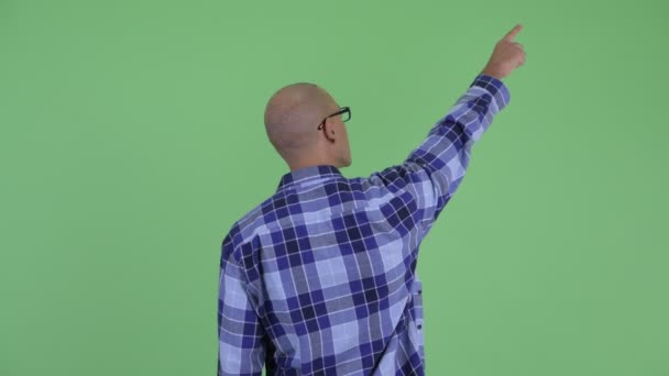 Вид сзади на лысого хипстера, указывающего пальцем — стоковое видео