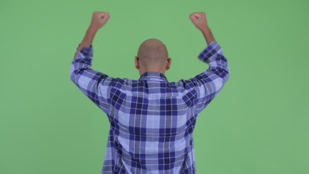 Achteraanzicht van gelukkige kale hipster man met fisten verhoogd — Stockvideo