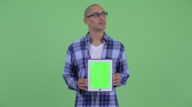 Mutlu kel hipster adam düşünme dijital tablet gösterirken