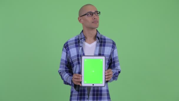 Glücklicher, glatzköpfiger Hipster-Mann denkt während er digitales Tablet zeigt — Stockvideo