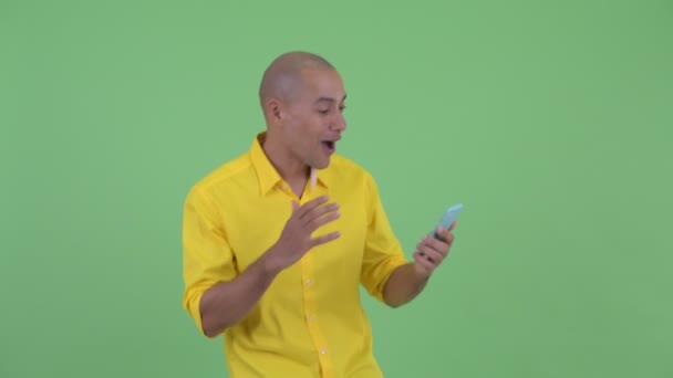 Bonito empresário careca feliz usando telefone e recebendo boas notícias — Vídeo de Stock