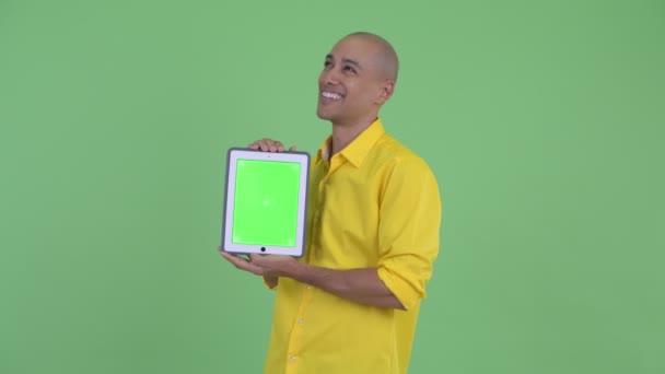 Счастливый красивый лысый бизнесмен думает, показывая цифровой планшет — стоковое видео