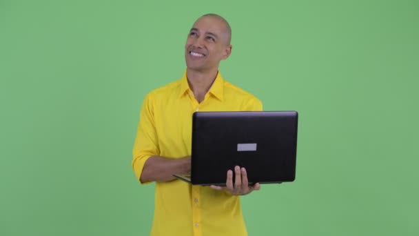 Счастливый красивый лысый бизнесмен думает во время использования ноутбука — стоковое видео