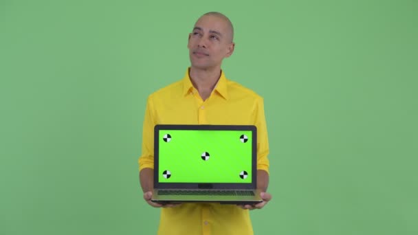 Feliz hombre de negocios calvo guapo pensando mientras muestra el ordenador portátil — Vídeos de Stock