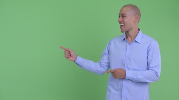 Happy bald multi ethnic businessman pointing finger and showing something — Stock Video