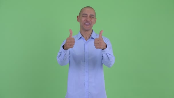 Щасливий лисий багатонаціональний бізнесмен дає великі пальці вгору і виглядає збуджено — стокове відео