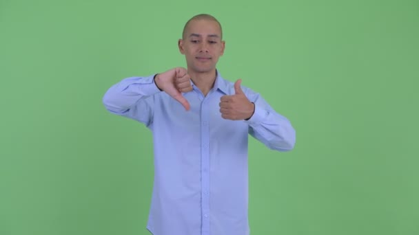 Confused bald multi ethnic businessman choosing between thumbs up and thumbs down — Stock Video