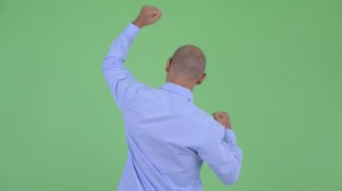 Yumrukları yükseltilmiş mutlu kel çok ırklı işadamının Arka görünümü