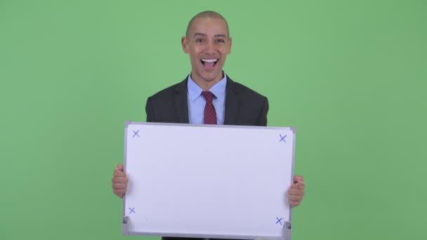 Happy bald multi ethnic businessman holding white board and looking surprised — Stock Video