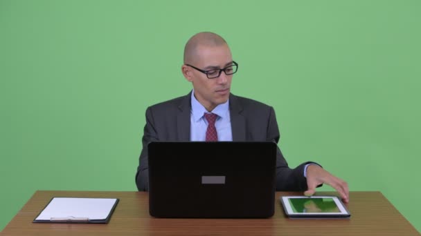Upptagen Bald multi etnisk affärsman multitasking på jobbet bakom skrivbord — Stockvideo