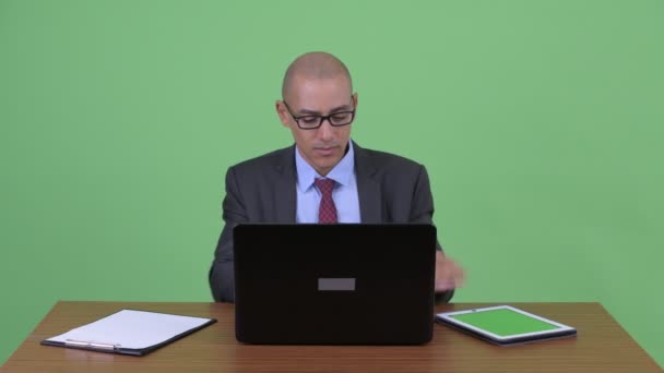 Geschäftiger multiethnischer Geschäftsmann mit Glatze telefoniert während er arbeitet — Stockvideo