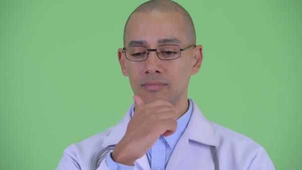 Лицо напряженного лысого многоэтнического мужчины врач думает и смотрит вниз — стоковое видео