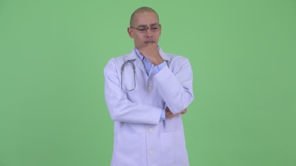 Estressado careca multi étnico homem médico pensando e olhando para baixo — Vídeo de Stock