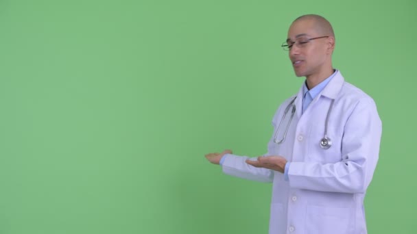 Feliz careca multi étnico homem médico mostrando para trás e dando polegares para cima — Vídeo de Stock