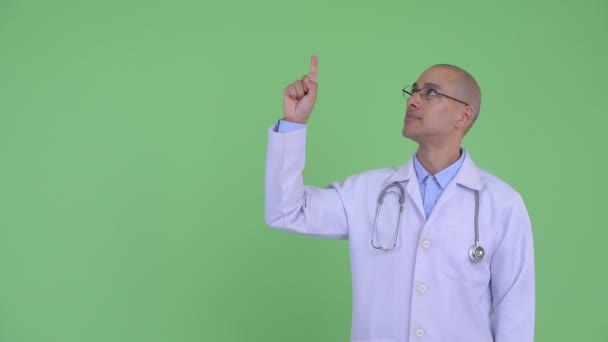 Feliz careca multi étnico homem médico apontando para cima e dando polegares para cima — Vídeo de Stock