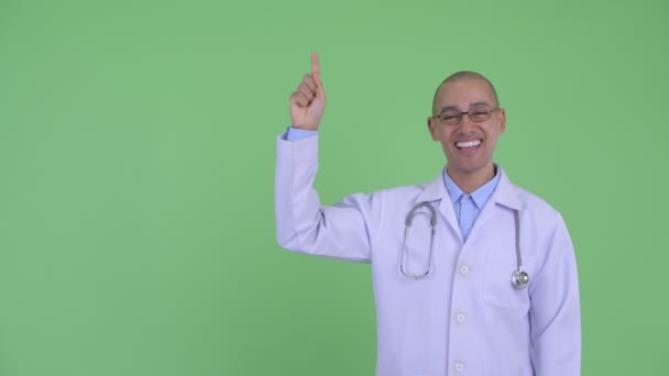 Happy bald multi ethnic man doctor talking while pointing up — Stock Video