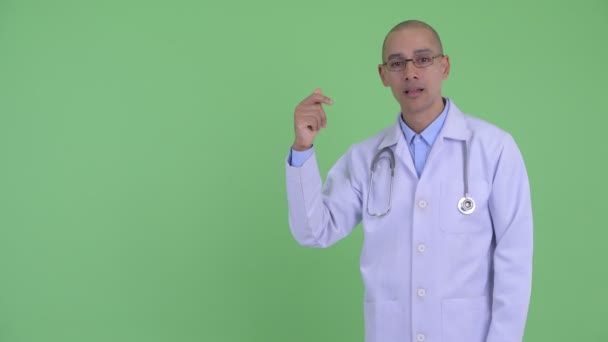 Счастливый лысый многонациональный врач щелкая пальцами и показывая что-то — стоковое видео