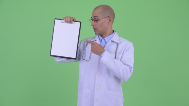 Happy bald multi ethnic man doctor showing clipboard and giving thumbs up — Stock Video