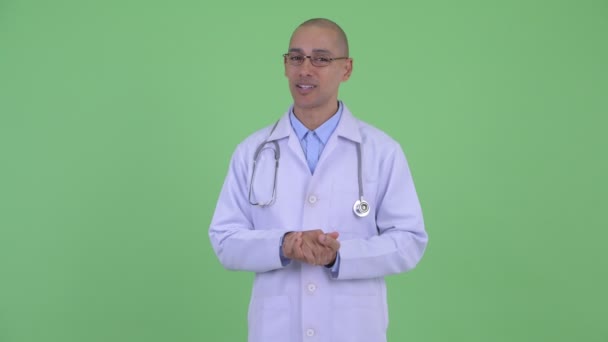 Szczęśliwy łysy wielu etnicznych mężczyzna lekarz prezentuje coś — Wideo stockowe