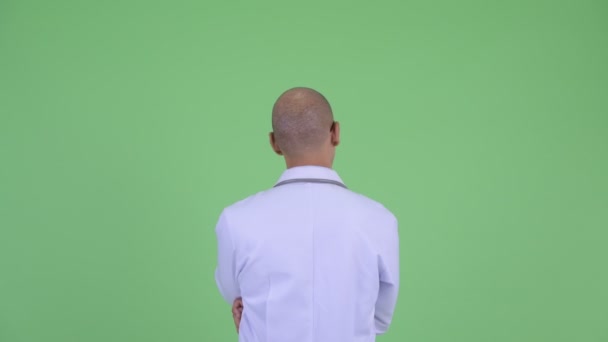 Вид сзади на лысого многоэтничного врача, указывающего пальцем — стоковое видео