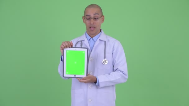 Ευτυχισμένος φαλακρός πολυεθνικός άνθρωπος γιατρός δείχνει ψηφιακό δισκίο και αναζητούν έκπληκτος — Αρχείο Βίντεο