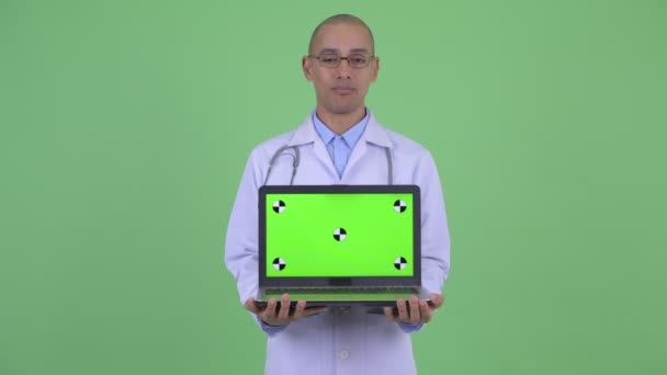 Щасливий лисий багато етнічний чоловік лікар розмовляє, показуючи ноутбук — стокове відео