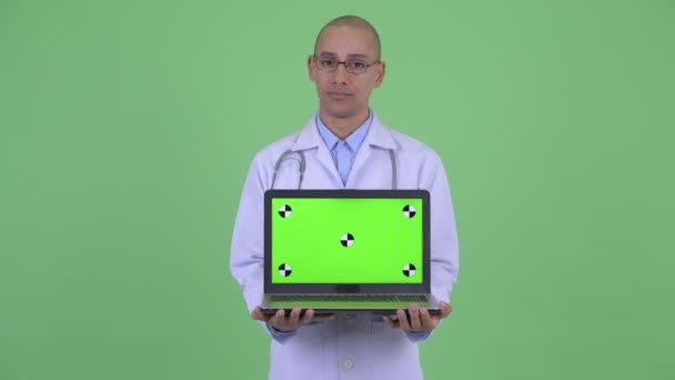 Стресс лысый многоэтничный врач показывая ноутбук — стоковое видео