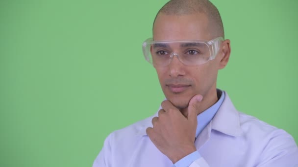 Face of Happy Bald multi etnisk man läkare med skyddande glasögon tänkande och tittar upp — Stockvideo