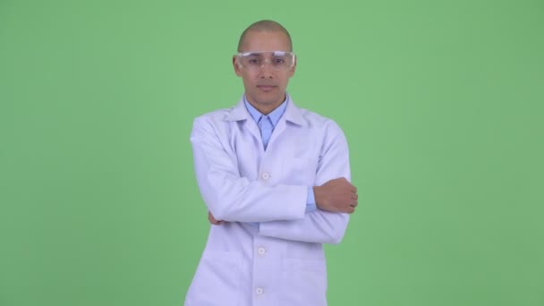 Happy bald multi ethnic man doctor with protective eyeglasses smiling with arms crossed — Stock Video