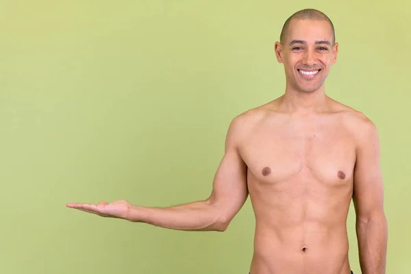 Felice calvo uomo multietnico mostrando qualcosa a torso nudo — Foto Stock