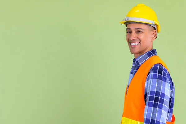 Вид профілю щасливого багатонаціонального працівника будівництва, який дивиться на камеру — стокове фото