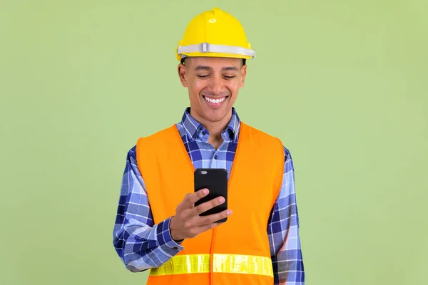 Щасливий багатонаціональний працівник будівництва, використовуючи телефон — стокове фото