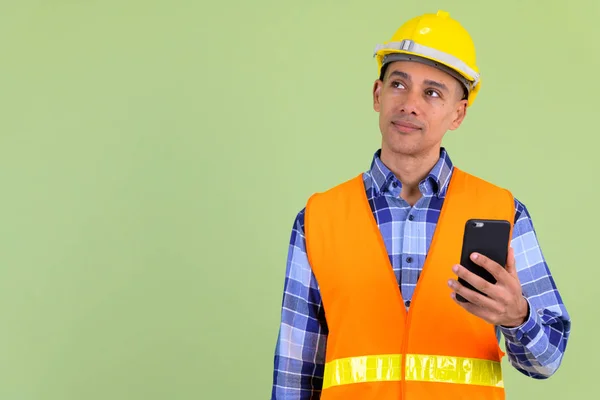 ハンサムな多民族男性建設労働者は、電話を使用しながら考える — ストック写真