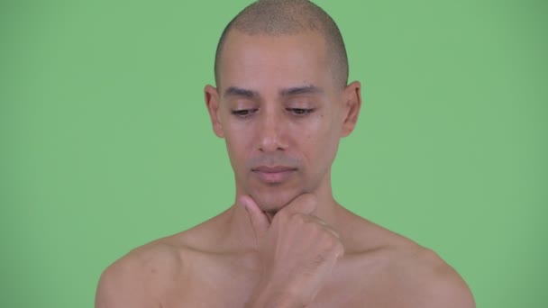 Gesicht eines gestressten glatzköpfigen, multiethnischen Mannes, der ohne Hemd denkt — Stockvideo
