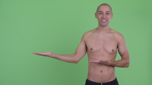 Счастливый лысый многонациональный мужчина без рубашки говорит показывая что-то — стоковое видео