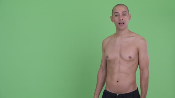 Счастливый лысый многонациональный мужчина без рубашки трогает что-то и выглядит удивленным — стоковое видео