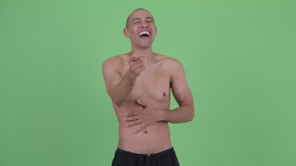 Счастливый лысый многонациональный мужчина без рубашки смеется и указывает на камеру — стоковое видео