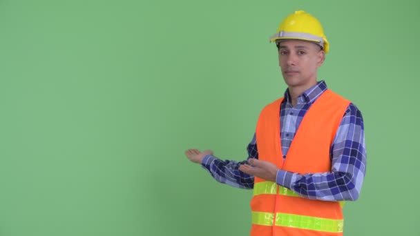 Stressed multi ethnic man construction worker showing to back — Stock Video