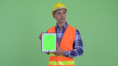 Mutlu çok etnik adam inşaat işçisi düşünme dijital tablet gösterirken