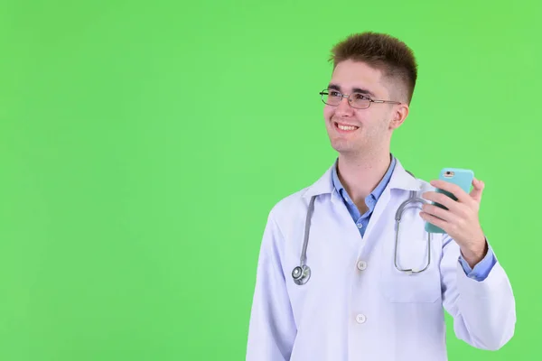 Gelukkig jonge man arts denken tijdens het gebruik van de telefoon — Stockfoto