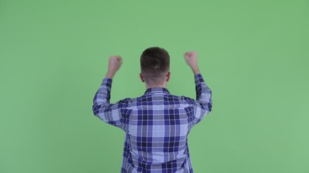 Задний вид счастливого молодого хипстера с поднятыми кулаками — стоковое видео